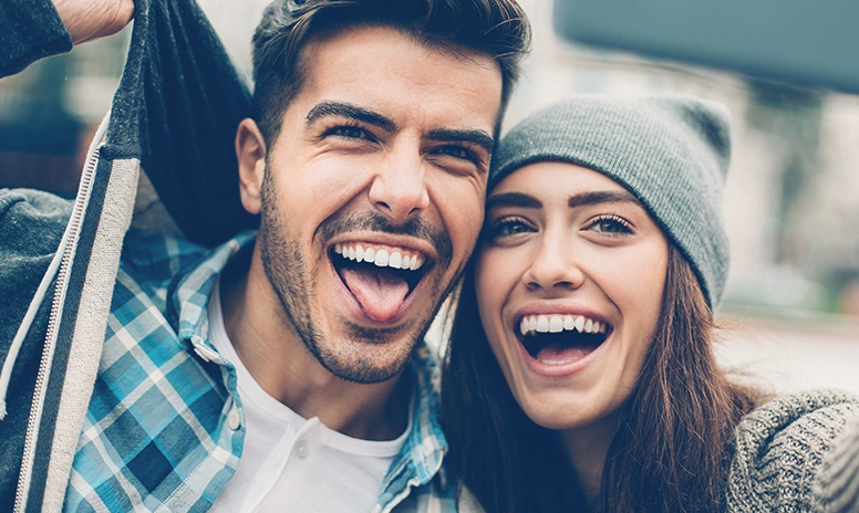 Attraktive junges, lachendes Paar mit schönen, geraden Zähnen