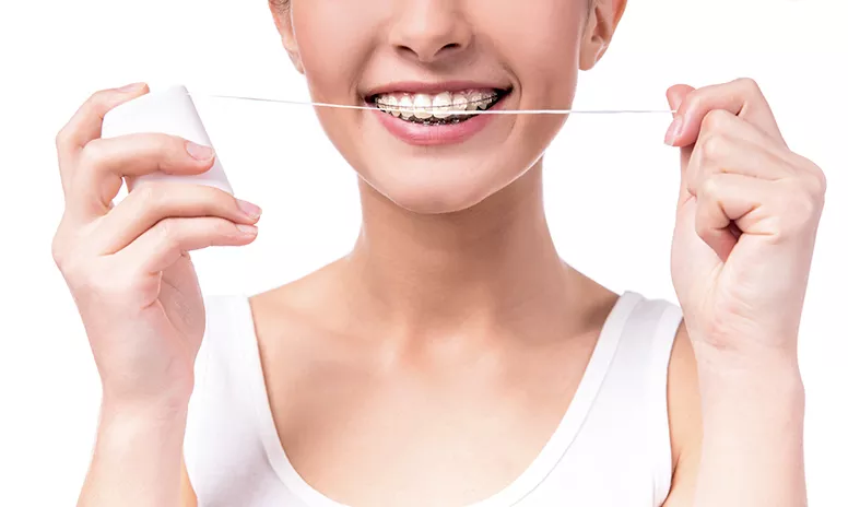 Frau mit Zahnspange bei Zahnpflege mit Zahnseide