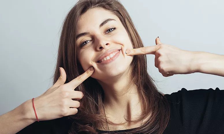 Teenager zeigt glücklich auf ihre Wangen ohne die Außenspange