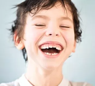 Kieferorthopäde München Dr. Dipsche | Herzhaft lachender Junge mit schiefen Zähnen
